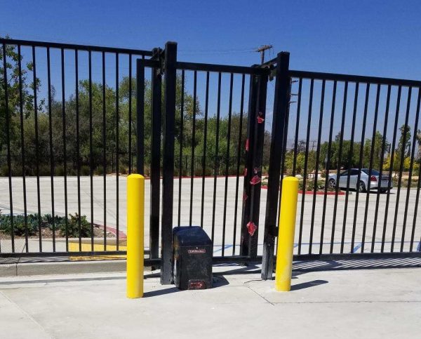 Sturdy black iron fencing lines a commercial property, featuring an automated gate system for enhanced security, provided by Inland Empire Fencing.