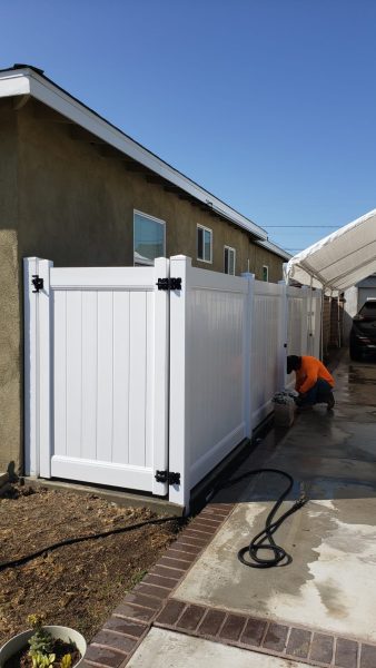Fencing professional from Inland Empire Fencing completing the installation of a white vinyl fence, enhancing property security and curb appeal.