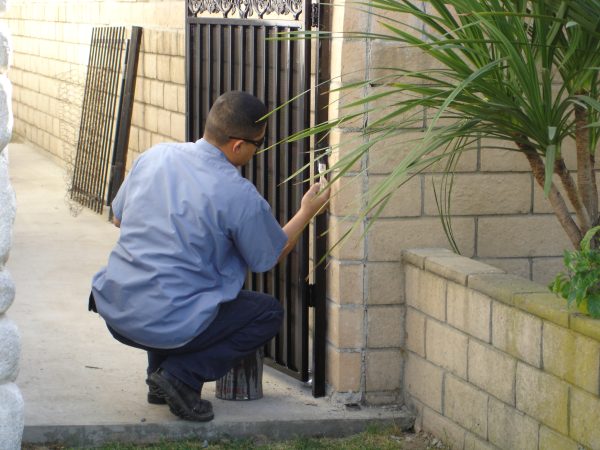 Fencing technician from Inland Empire Fencing repairing a gate post, ensuring structural integrity and longevity of fencing products.