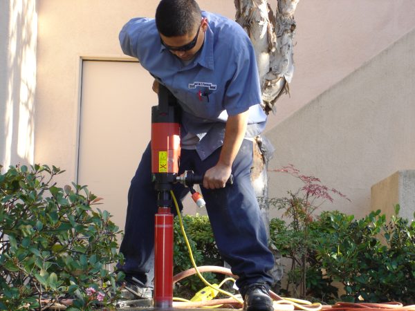 Fencing specialist from Inland Empire Fencing using a leveling tool on a fence post, ensuring precise installation for optimal fence alignment.