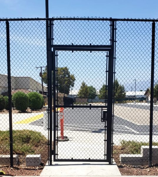 Black chain-link security gate with barbed wire, ensuring controlled access to a secure area, reflecting Inland Empire Fencing's commitment to safety and perimeter protection.