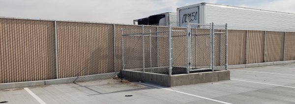 Enclosed dumpster area with chain-link fencing and gated access, installed by Inland Empire Fencing for cleanliness and restricted access in a commercial space.
