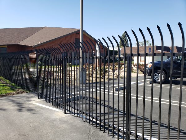 Curved top iron fence designed by Inland Empire Fencing, offering elegant security solutions for a commercial establishment's perimeter.