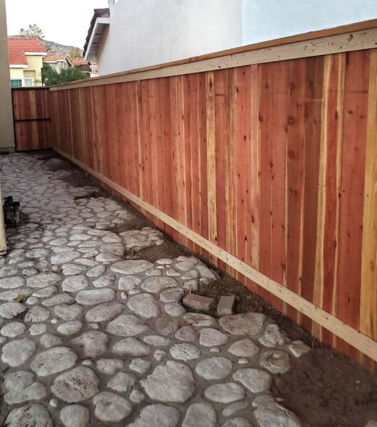 A rustic wood fence entryway with vertical planks, providing a warm and inviting access point that features Inland Empire Fencing's residential fencing expertise.