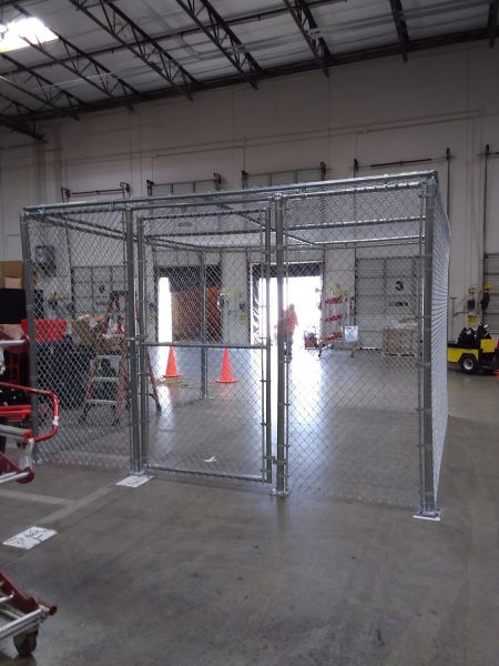Indoor wire cage with a secure gate, providing a safe and visible storage solution within a warehouse, expertly constructed by Inland Empire Fencing.