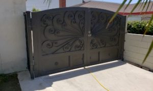 Artistic metal gate with ornate design details, providing secure access to a residential driveway.