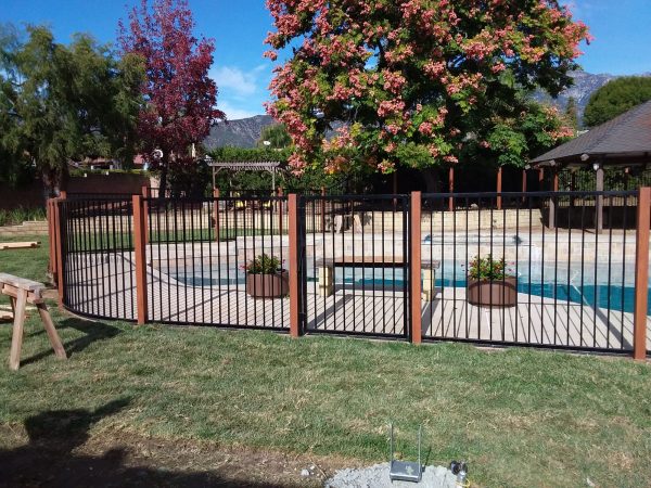 Ornamental iron fence surrounding a residential pool area, combining safety with elegant design, a specialty of Inland Empire Fencing.