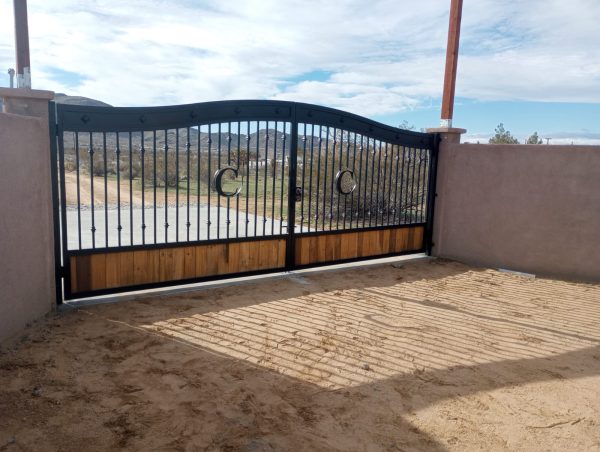 Dual-panel iron gate combining wood elements and decorative ironwork, creating a stylish and private entryway for a driveway.